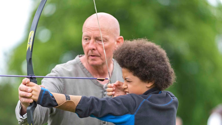 Boy trying archery at the Medieval Festival at Tattershall Castle, Lincolnshire